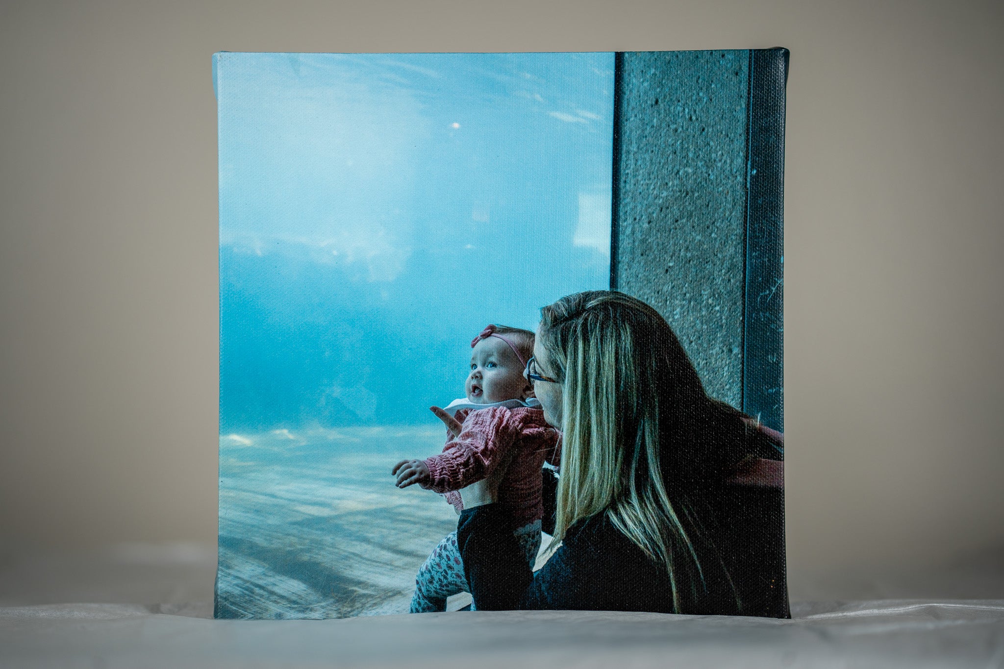 Custom 8x8 canvas print of a mother and child at an aquarium, displayed on a table, showcasing Modern Canvas Company's high-quality materials.